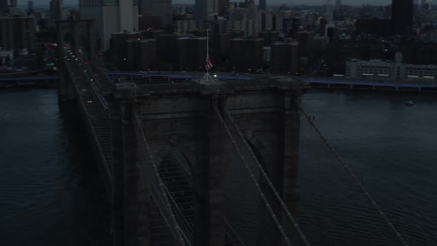 Flag flies on suspension bridge leading to downtown skyscrapers