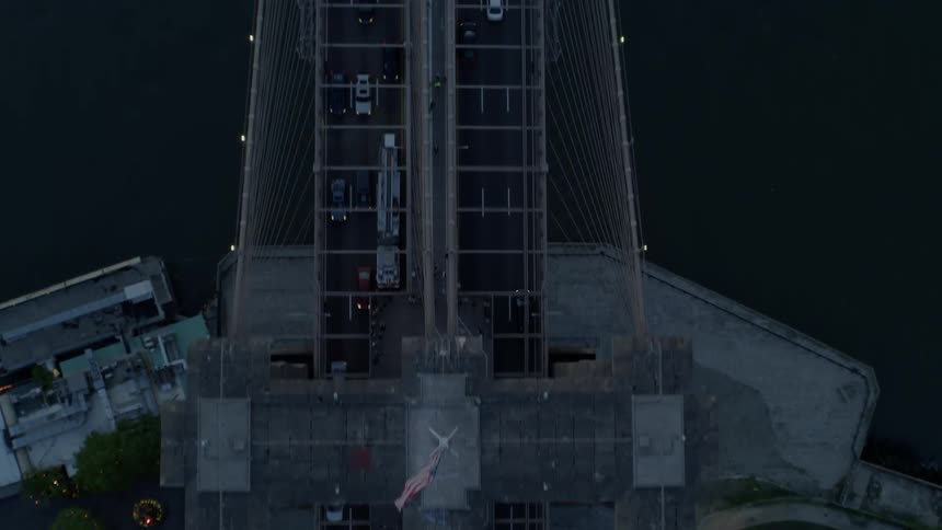 Birds eye view of traffic on suspension bridge over river at night