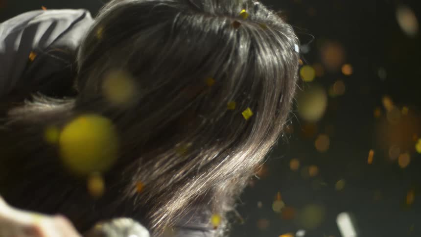Gold confetti falls around a woman holding a microphone