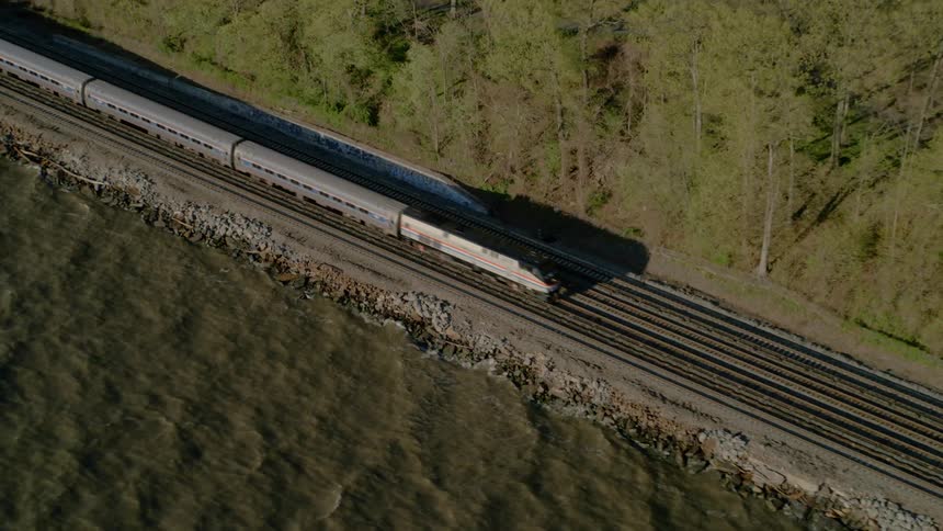 A train travels a track that runs along the coast of a body of water