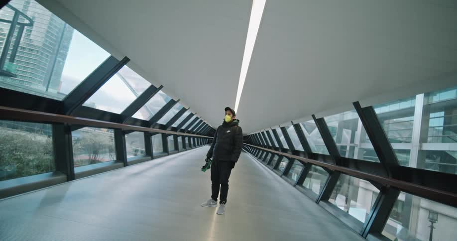 Man wearing a surgical mask stands in a corridor in a city