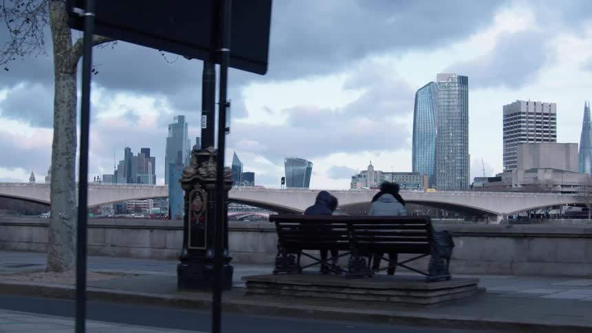 People on a city sidewalk with the skyline in the distance