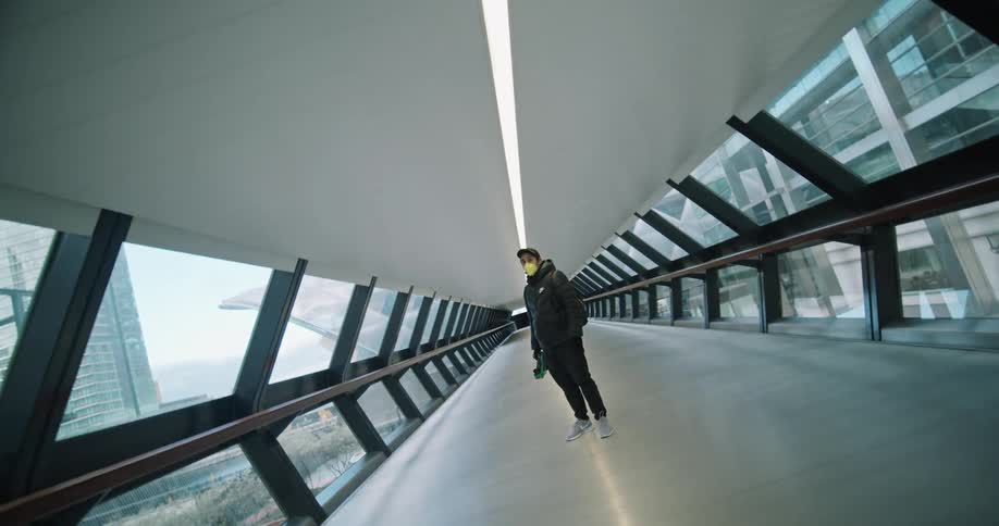 Man wearing face mask stands in the middle of a pedestrian overpass