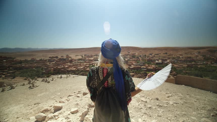 A woman fans her face as she watches the town ahead