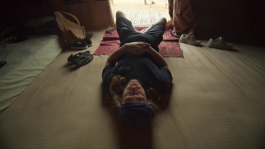 A person lays down slowly in meditation in a yurt style tent