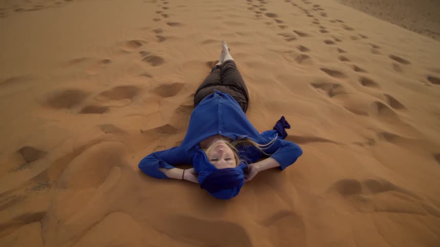 Woman laying on sand dune in desert