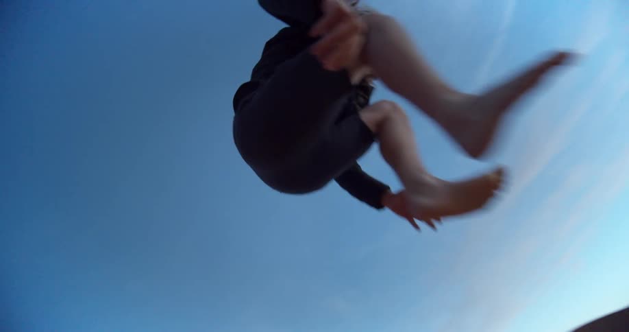 A man takes a running leap off of a sand dune in the desert as friends watch