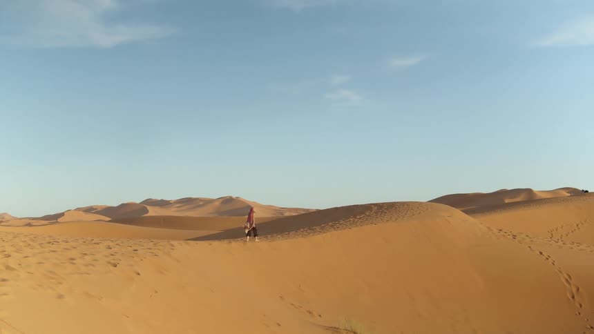 Person walking across sand dunes in desert