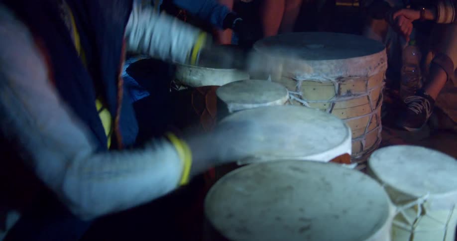 Men at night sitting around playing drums