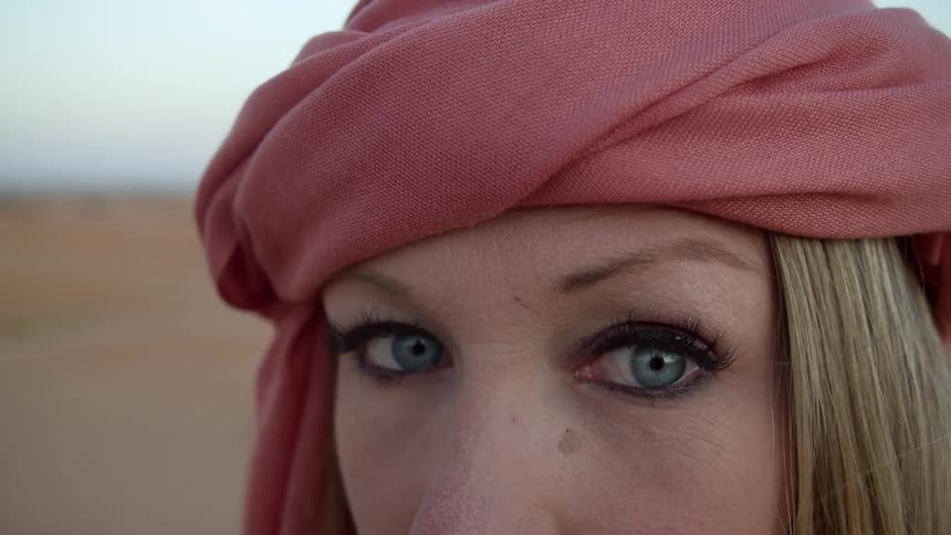 Blue eyed woman wearing a red headscarf stares at the camera