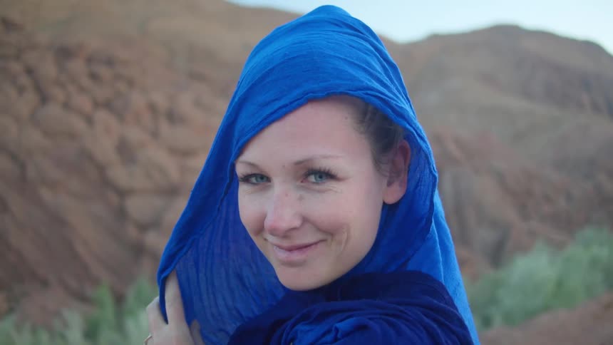 Blue eyed woman wearing a blue scarf poses for the camera
