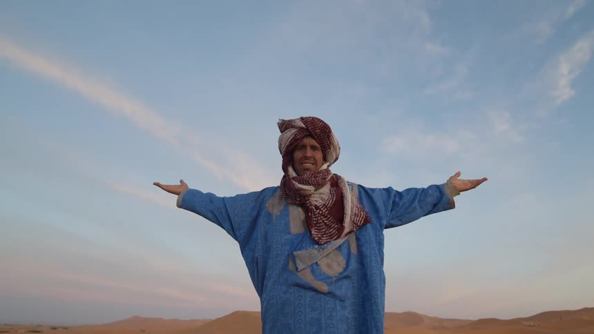 A man stands in the desert with his arms open wide