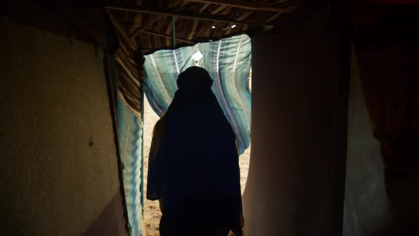 A person walks out of the tent into the desert