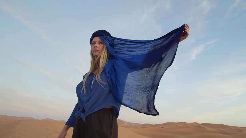 A model holds onto a blue head scarf as she posed in the desert