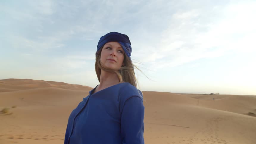 A woman stands in the desert and looks around