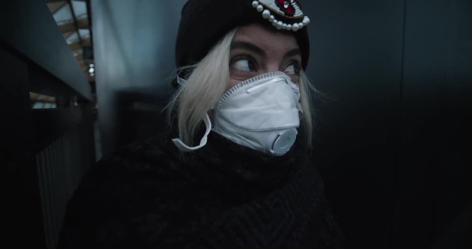 Blonde woman wearing a face mask turns her gaze away