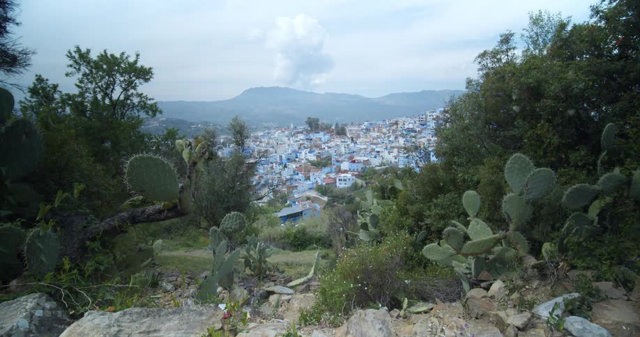 A plume of smoke hangs over a mountain beyond a small town