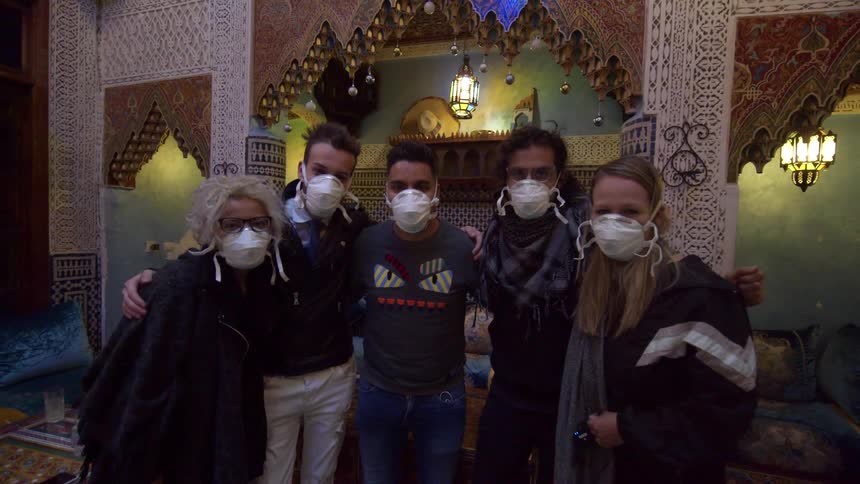 Group of friends wearing face masks stand together in moroccan restaurant