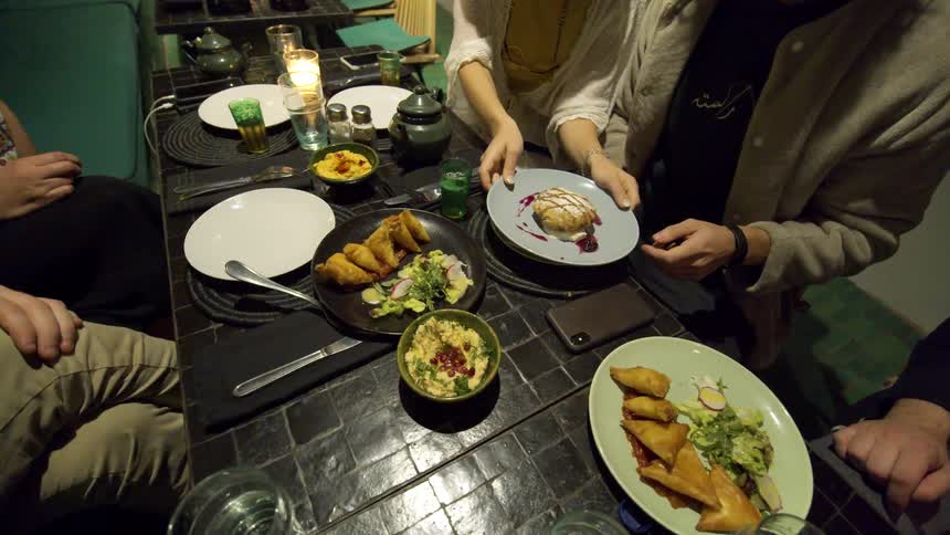 A woman placing a plate of desert in front of the man sitting next to her at a table in a restuarant