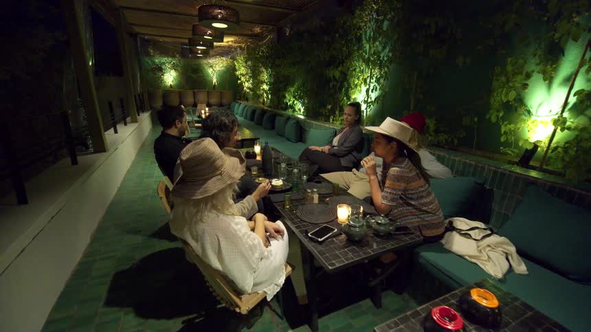 A group of friends relaxes in a restaurant sitting on cushioned benches and chairs