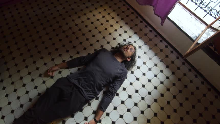A man lying on the floor beneath the window of a room