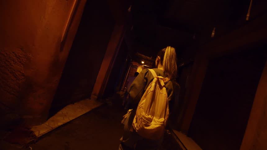 Woman walks in the narrow dark street at night