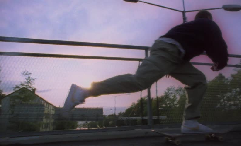 Three teens ride skateboards on an elevated walkway