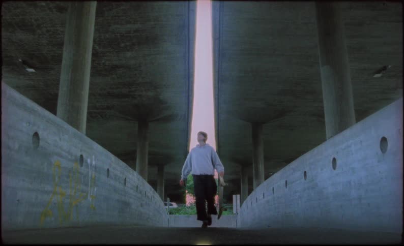 Skateboarder under freeway overpass pauses to look up