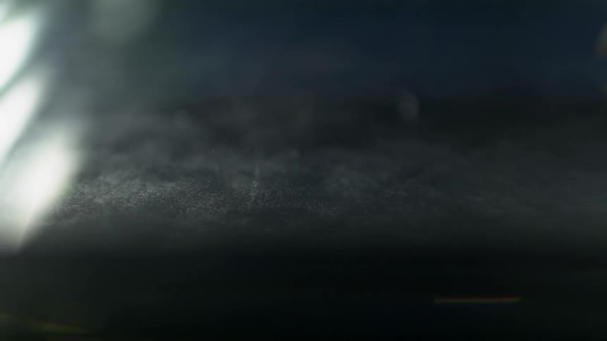 The moon and rolling clouds are reflected on a glass surface