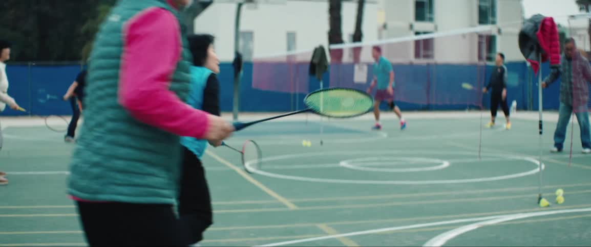 Asian women playing badminton on a court in the city