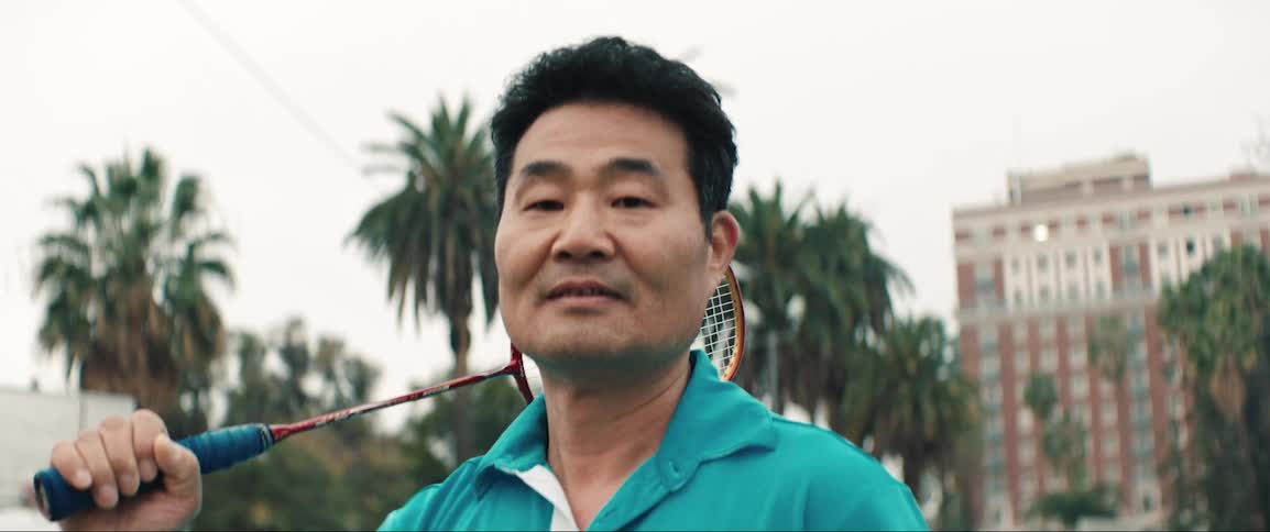 Man poses with badminton racquet over shoulder