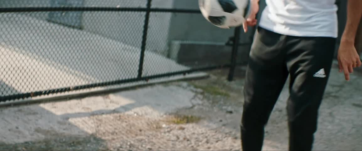 An athlete is playing soccer outdoors by himself