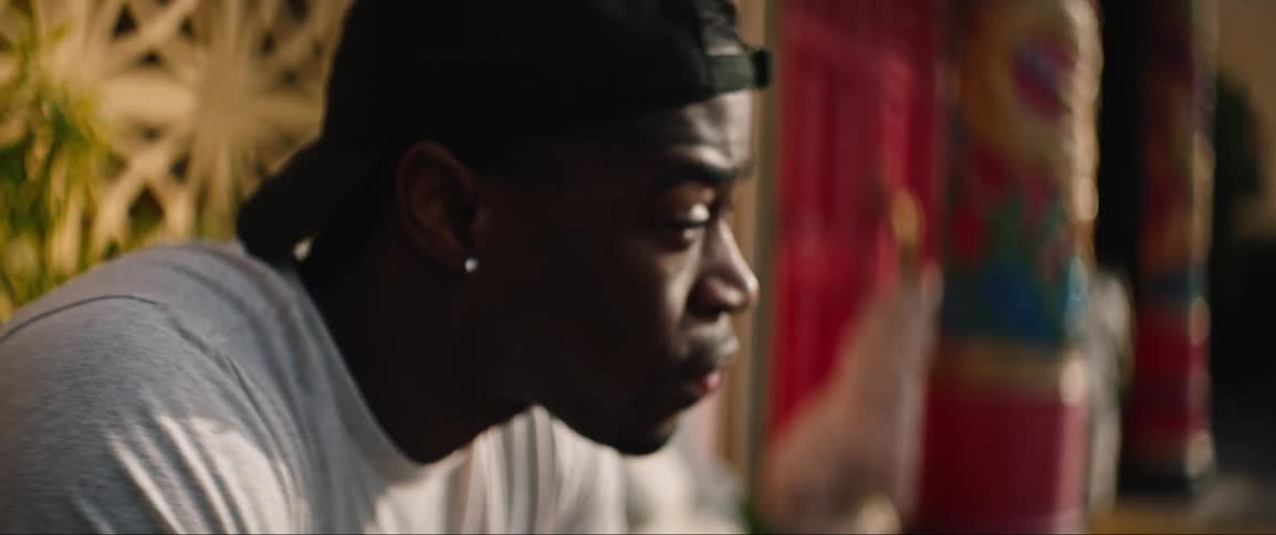 A black man sits indoors and looks at his surroundings