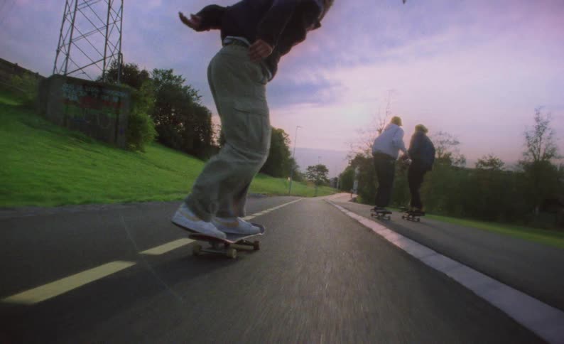 A group of young skateboarders ride down the road on skateboards