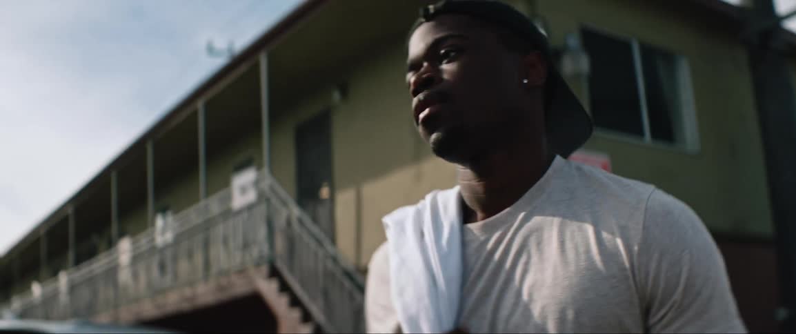 A black man walks away from a building in a neighborhood