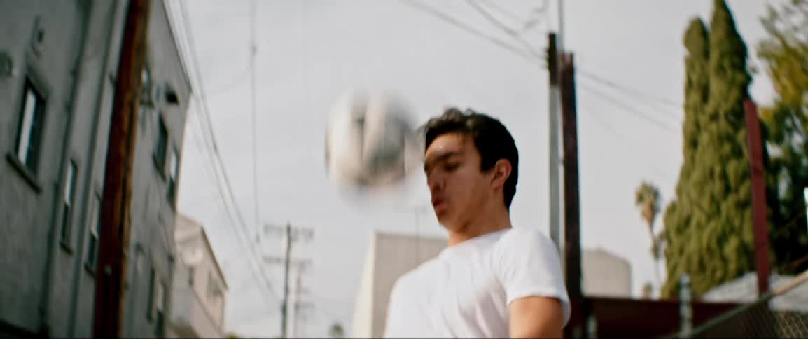 Young man dribbling soccer ball in alley