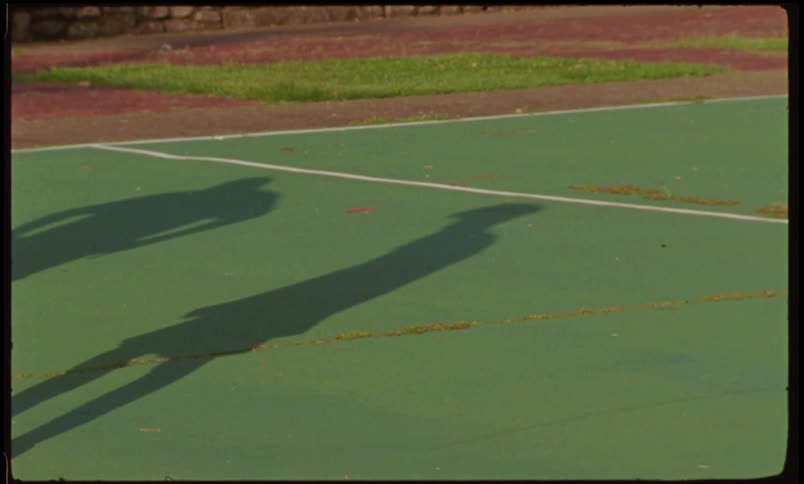Shadows of two people standing on an outdoor court
