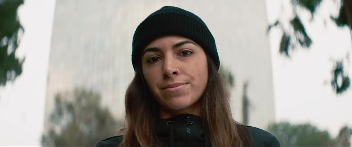 A female teenager stands outdoors in a city