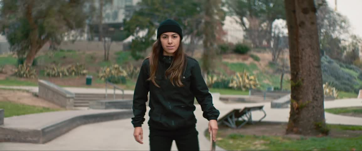 Young woman rides skateboard in park