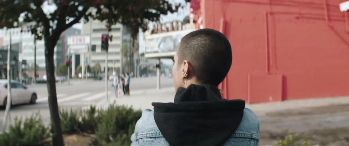 A woman walks on the sidewalk to the corner