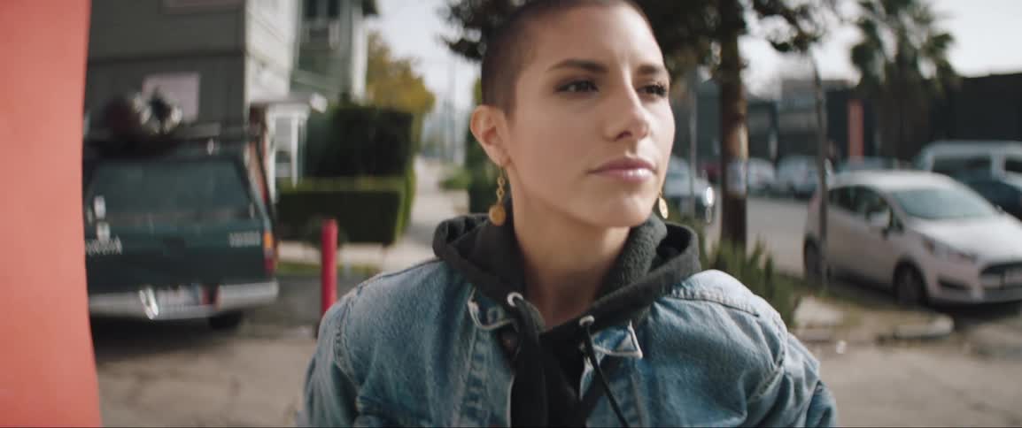 Young woman wearing denim jacket walks down the street