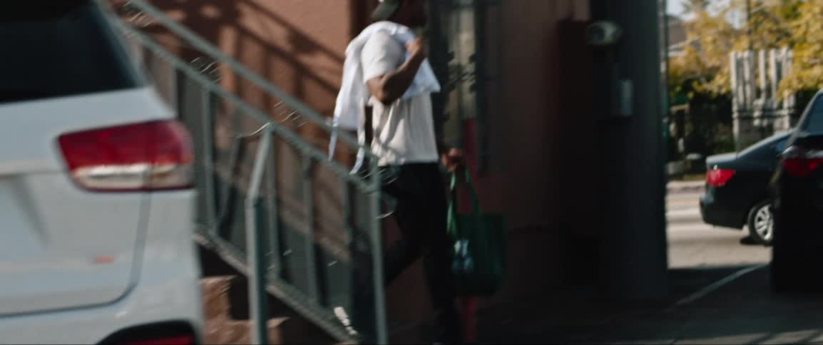Young man carrying shopping bag with white apron over shoulder