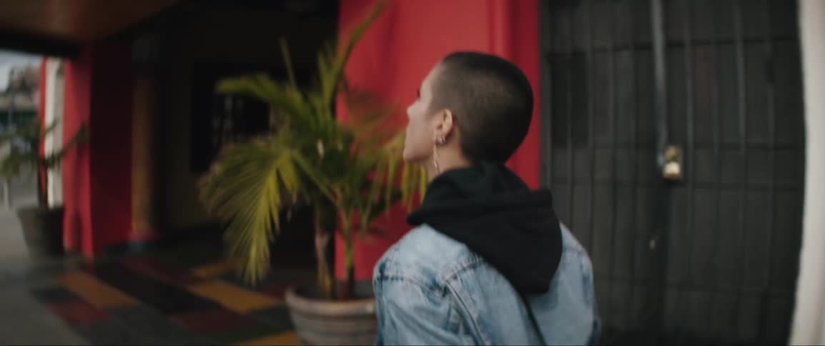 Woman wearing denim jacket walks on the street and enters a theater