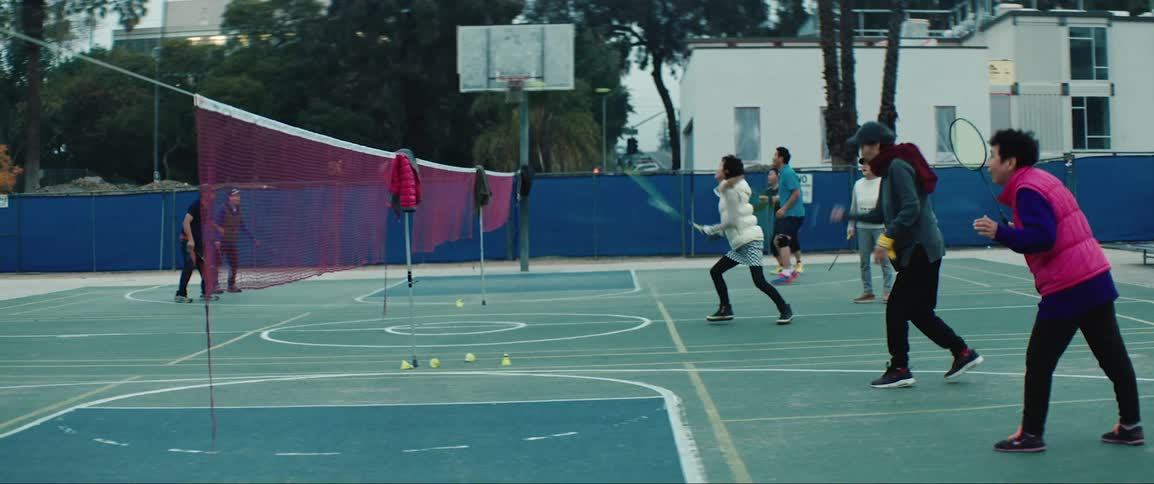A group of teenagers hit badminton birds over a net
