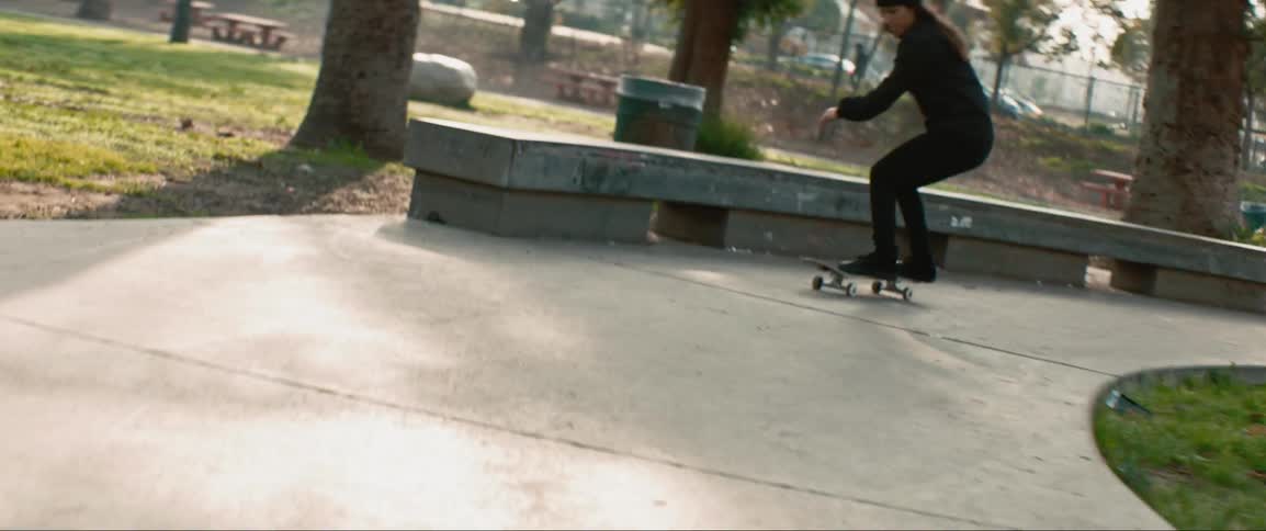 A person performs skateboard tricks in a public park pathway