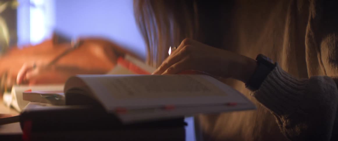 A white woman sits at a table and flips through pages in a book