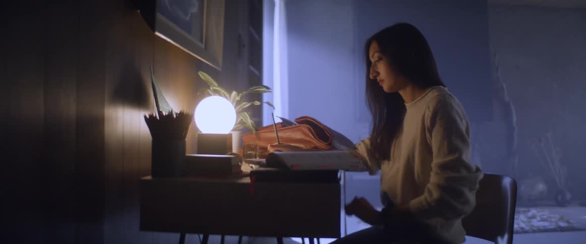 Young woman writing at desk with lamp