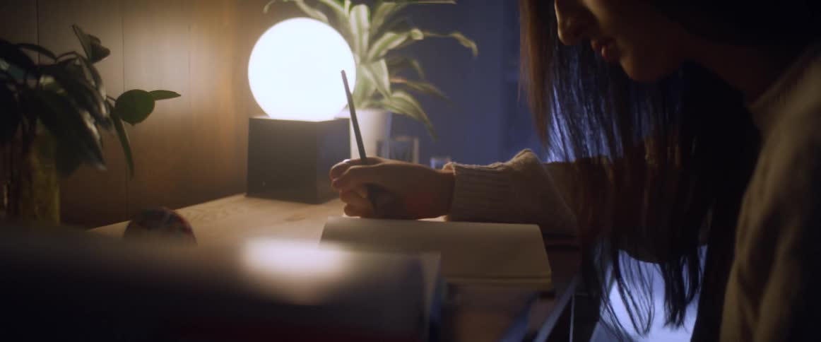 A woman is writing in a notebook at her desk