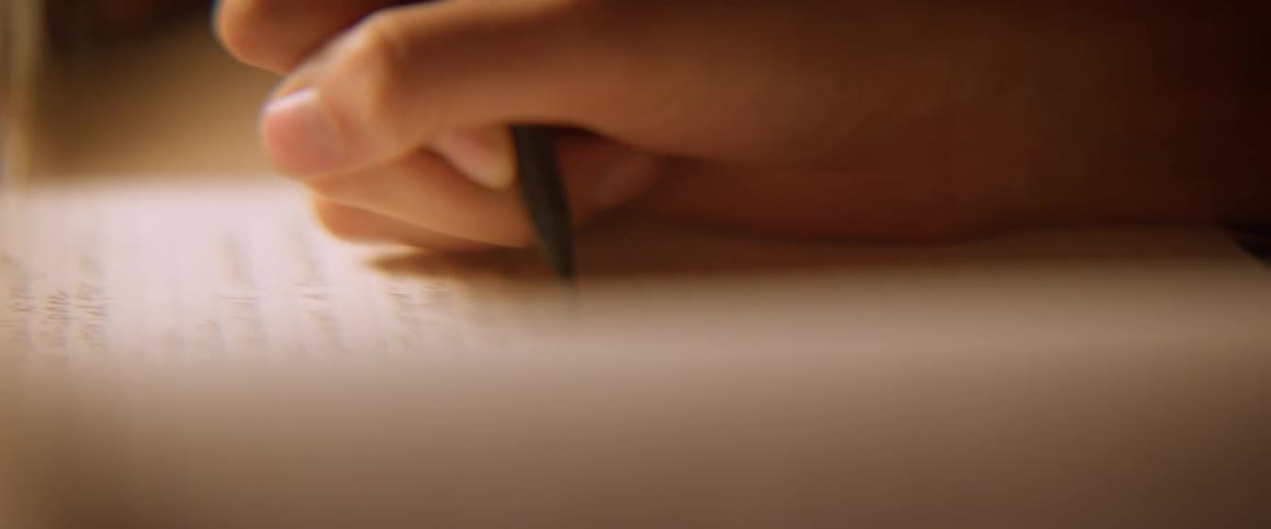 A person is writing with a pen on a piece of paper