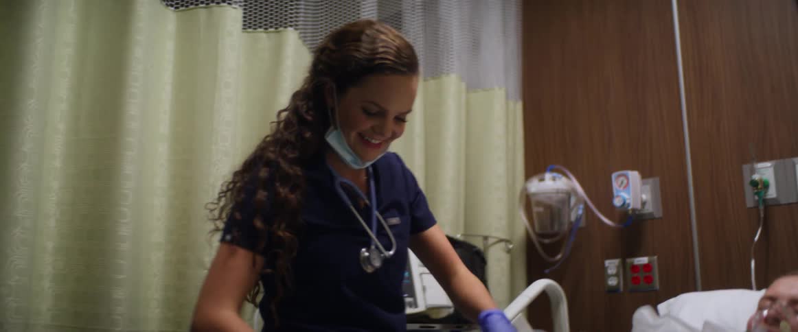 A nurse attends to a patient in a hospital bed